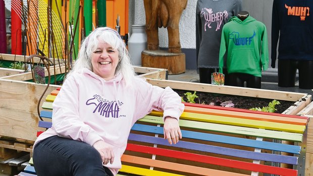 Francine Riesen sitzt mit einem ihrer selbstbedruckten Pullover vor ihrem Laden in Burgistein BE. Diesen kann man wegen seiner farbenfrohen Präsentation fast nicht verfehlen.(Bild Jasmine Baumann)