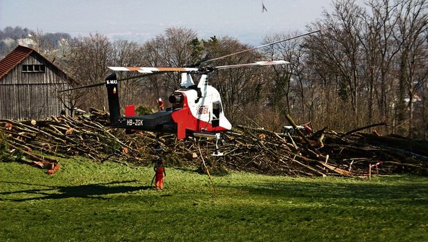 Zwischenlandung des Helikopters mit dem Übernamen «fliegenden Kran» bei Wienacht-Tobel. Er vermag mehr Gewicht zu Tragen als er Eigengewicht hat. Bäume fliegen im Appenzellerland durch die Luft. Im Hintergrund das sanktgallische Dorf Thal am Buechberg. (Bild: Hansruedi Wieser)