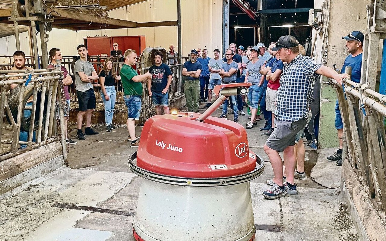 Der automatische Futterschieber «Wäutu» lässt sich von den Besuchenden auf dem Sonnhaldenhof nicht stören, während Betriebsleiter Marc Grüter (im grünen T-Shirt) erklärt.