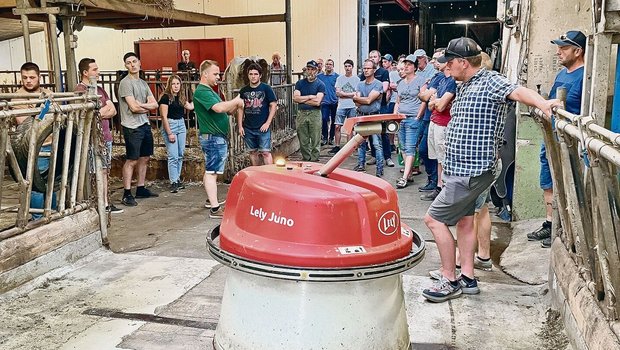 Der automatische Futterschieber «Wäutu» lässt sich von den Besuchenden auf dem Sonnhaldenhof nicht stören, während Betriebsleiter Marc Grüter (im grünen T-Shirt) erklärt.