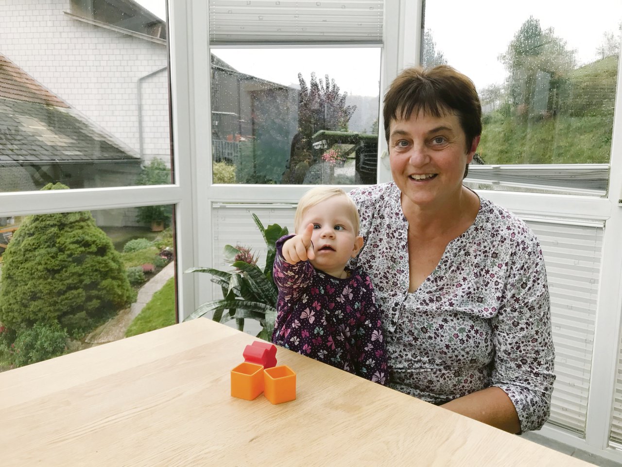 Doris Bächtold mit ihrem Enkelkind Emelie an einem verregneten Tag am Stubentisch. Sie schätzt die Zeit mit ihr sehr und hütet sie jeden Dienstag.(Bild Franziska Jurt)