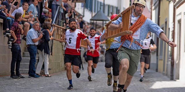 Die Läufer mit den über 8 Meter langen Chriesileitern kurz vor der ersten Kurve, anlässlich des Zuger Chriesisturms 2018. (Bilder zVg)