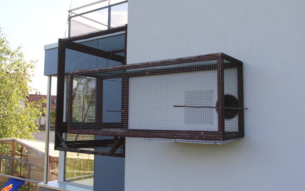Um Tieren den Aufenthalt im Freien zu ermöglichen, können Volierenbauer auch solche Verbindungskanäle an Aussenmauern bauen. 