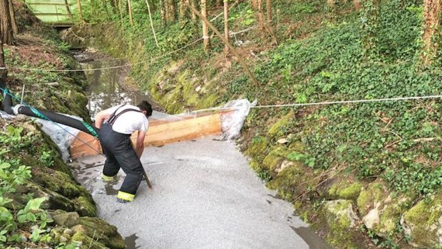Ein Feuerwehrmann errichtet eine Sperre in einem Bach nachdem Gülle ausgelaufen ist. (Bild: Kantonspolizei Thurgau)