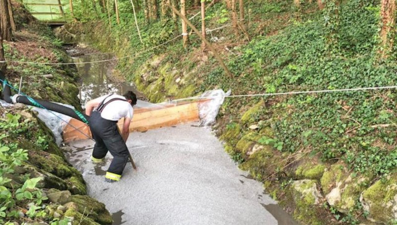 Ein Feuerwehrmann errichtet eine Sperre in einem Bach nachdem Gülle ausgelaufen ist. (Bild: Kantonspolizei Thurgau)