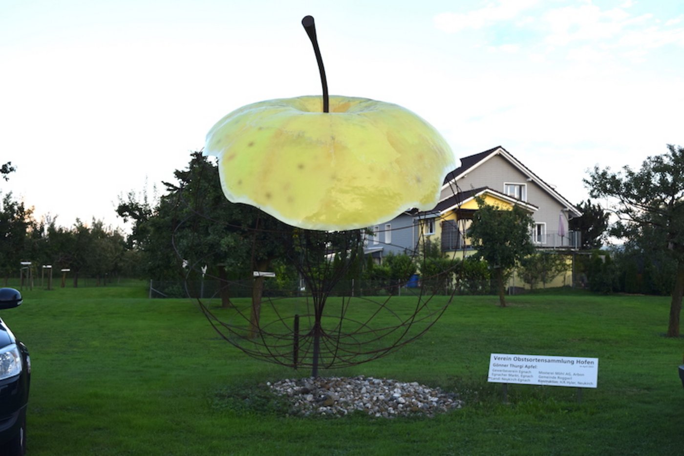 Ein grosser Apfel aus Drahgeflecht steht am Rande der Obstparzelle und heisst die Besucher willkommen.