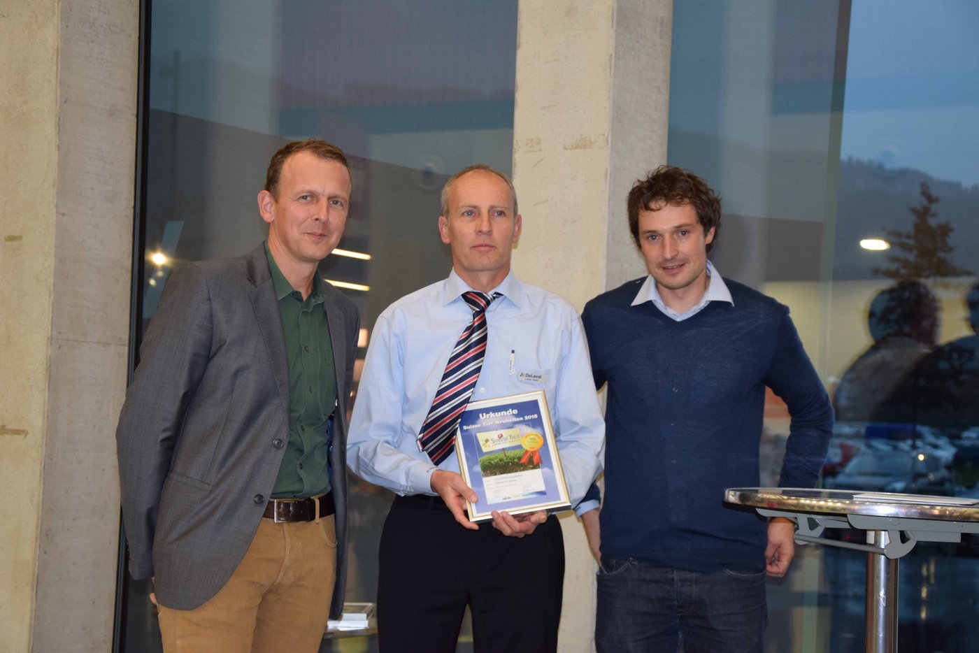 De Laval gewann mit ihrem Normroboterstall: Hier Lukas Suter (Mitte) und Urs Schmid (rechts) mit Adrian Krebs von der "BauernZeitung". 