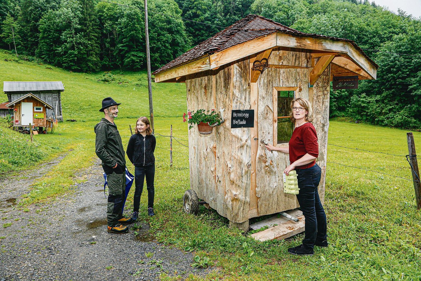Oskar, Svenja und Antonia Bissig bei ihrem Hofladenhüttli, das günstig neben einem Wanderweg gelegen ist. (Bild Erika Rebsamen)