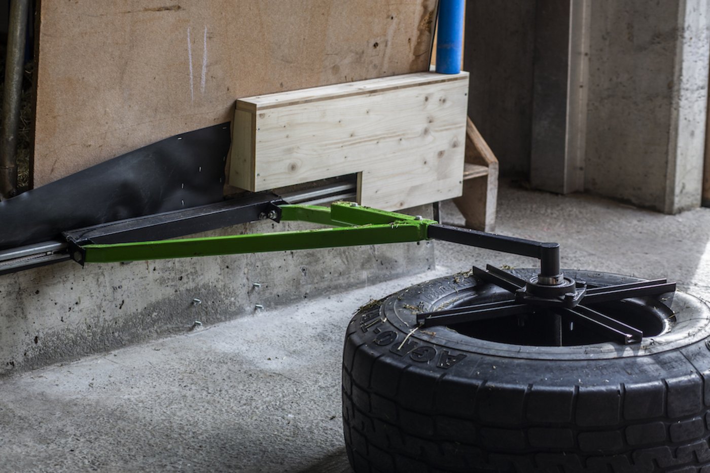 Der Futterschieber ist ein alter Anhänger-Pneu. Er ist mit einem Metall-Gestänge verbunden und läuft in einer Torschiene. Der Antrieb erfolgt über eine Winde. 