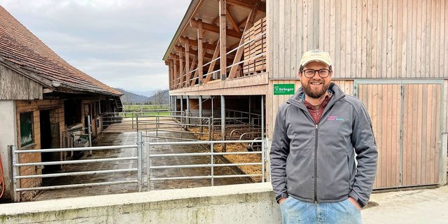 Christof Bühler vor dem Mutterkuhstall (vorne) und Pferdestall (hinten). Im alten Stall wurde nur innen investiert, und zwar in Liegeboxen, Fressachse und Abkalbebox.