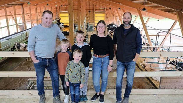 Martin und Andrea Blaser mit ihren Kindern Niklas, Magnus und Linus sowie Markus Schafroth (v. l. n. r.) in ihrem neu gebauten Stall. Ganz links ist das obenliegende Futterband zu sehen.
