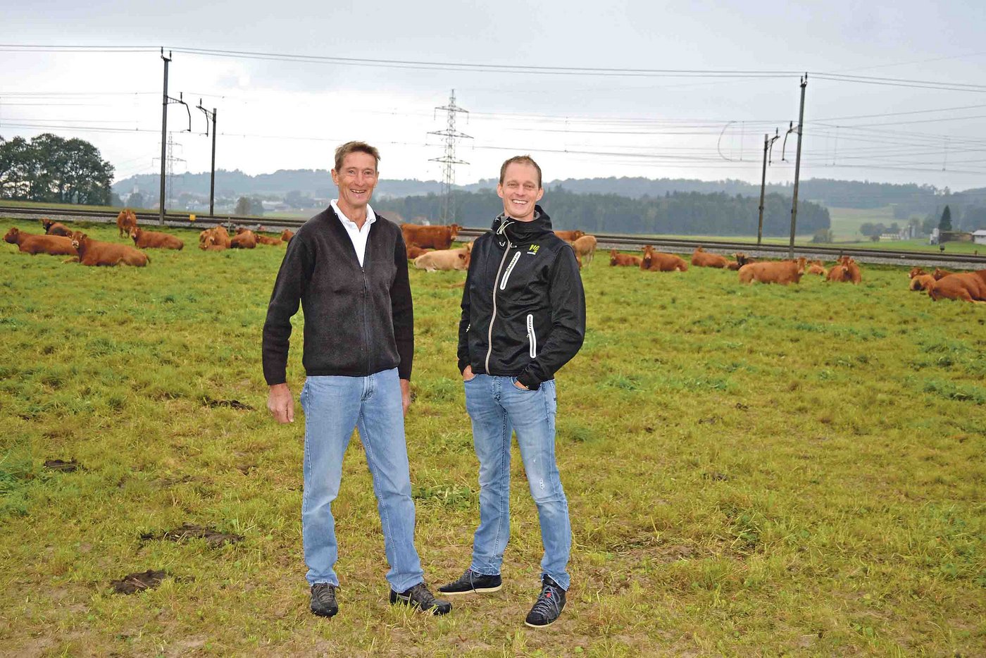 Hans Adler (links) hat schon vor zwölf Jahren auf Mutterkuhhaltung umgestellt. Sein Sohn Pirmin führt seit dem 1. Januar den Betrieb. Im Hintergrund ihre Limousin-Herde mit 38 Mutterkühen. (Bild Peter Fankhauser)