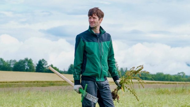 Kilian Baumann steht in Arbeitskleidung auf einem Feld.