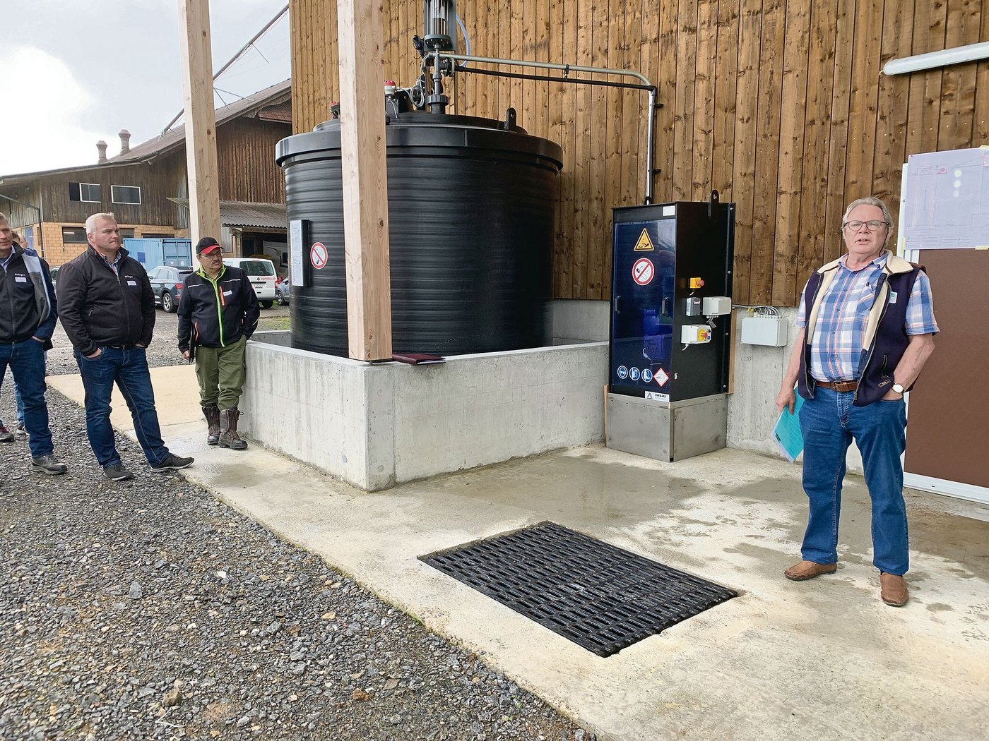 Edi Arnold erklärt die Funktion der Gülleansäuerung. Hinten der Säuretank, rechts die Pumpe mit der gesamten Steuerung. Von hier wird die Schwefelsäure in die Gülle eingegeben. (Bilder Josef Scherer)