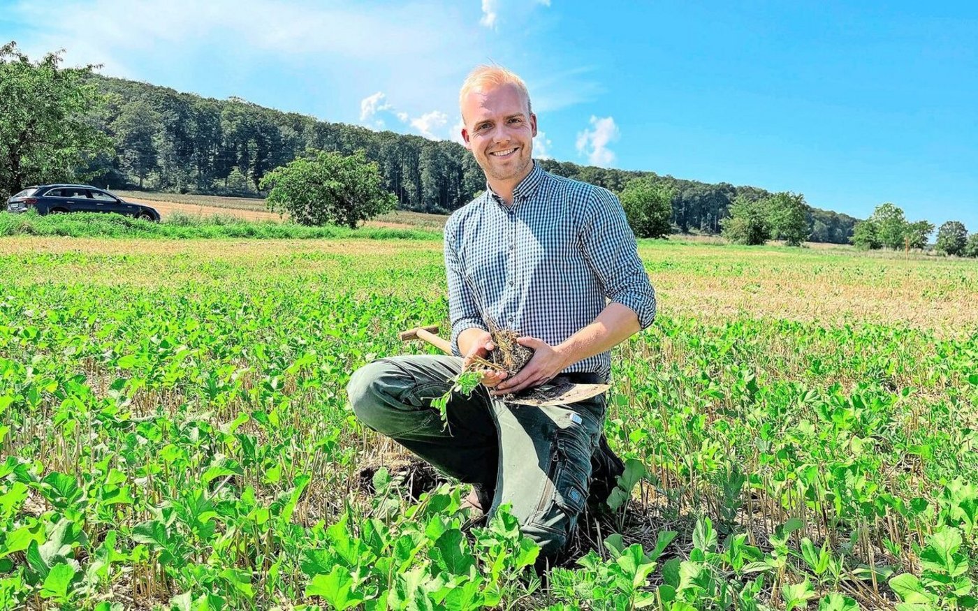 Der Junglandwirt mit dem Spaten auf dem Stoppelfeld: Ein Stich in den Boden zeigt eine gute Durchwurzelung, die lebenden Pflanzen schützen den Untergrund vor Sonne und Hitze.