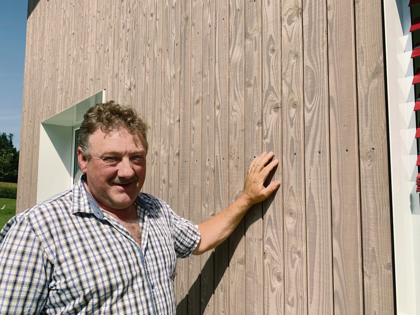 Adolf Koller weist auf die Vorteile der vorvergrauten Fassade hin. So verfärbt sich das Holz nicht mit der Witterung. 