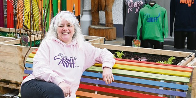 Francine Riesen sitzt mit einem ihrer selbstbedruckten Pullover vor ihrem Laden in Burgistein BE. Diesen kann man wegen seiner farbenfrohen Präsentation fast nicht verfehlen.(Bild Jasmine Baumann)