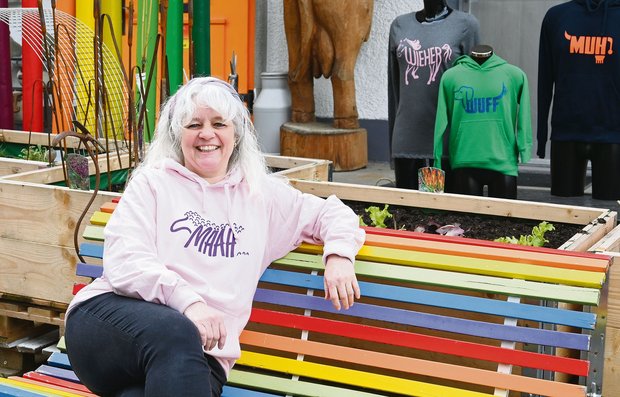 Francine Riesen sitzt mit einem ihrer selbstbedruckten Pullover vor ihrem Laden in Burgistein BE. Diesen kann man wegen seiner farbenfrohen Präsentation fast nicht verfehlen.(Bild Jasmine Baumann)