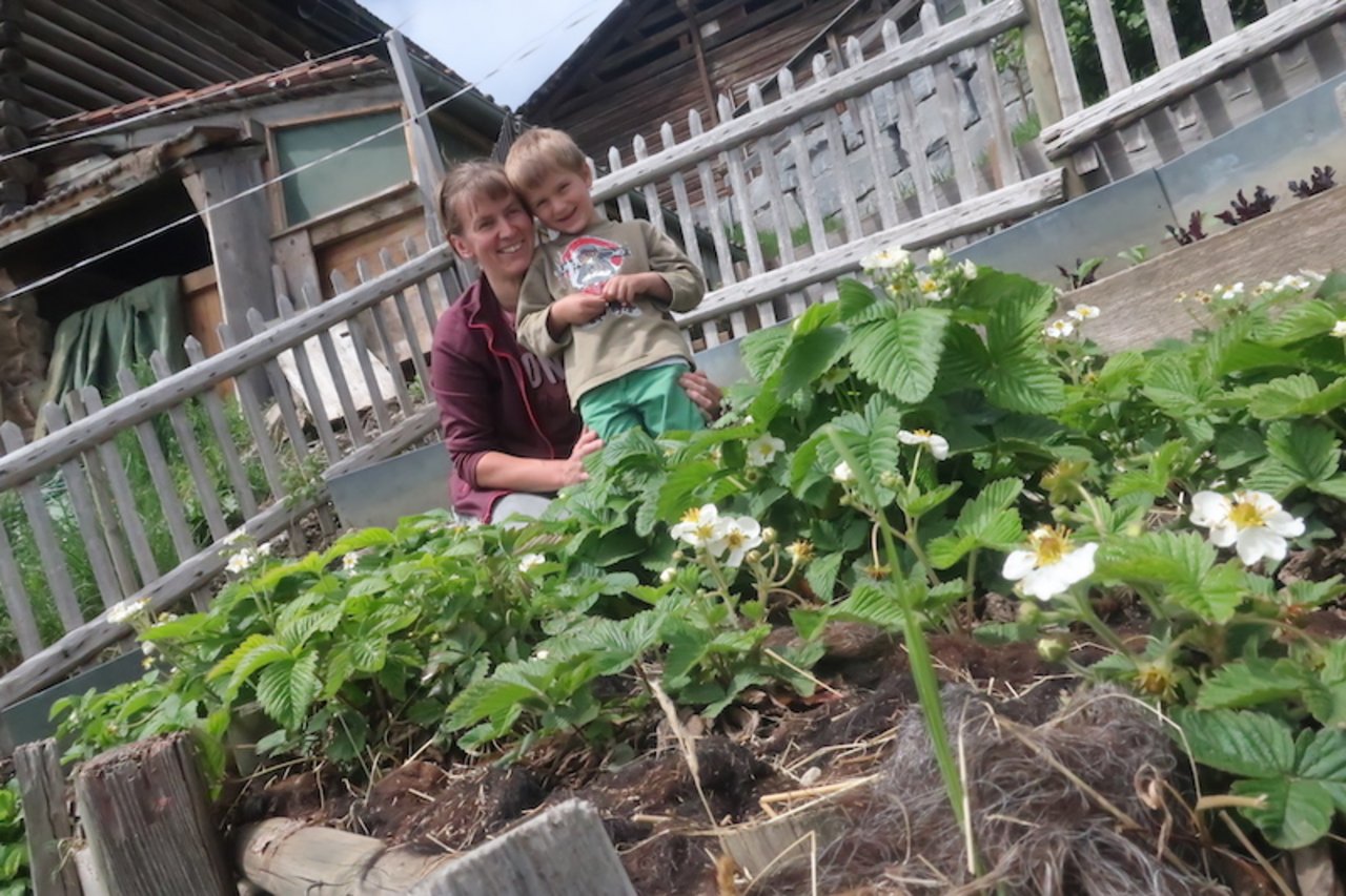 Silvia Moser mit ihrem jüngsten Kind, Simon Abraham, im grossen Garten für die Selbstversorgung.