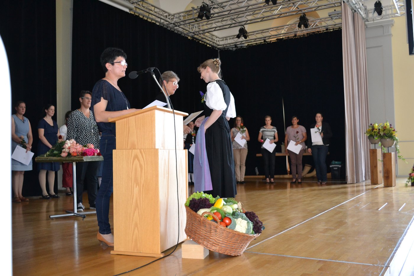 Fachausweisübergabe. Regula Mürner erhält den von Jeanette Zürcher-Egloff (Verantwortliche Bildung vom SBLV) ihren Fachausweis. Am Mikrofon Christine Gerber (Prüfungsleiterin SBLV)