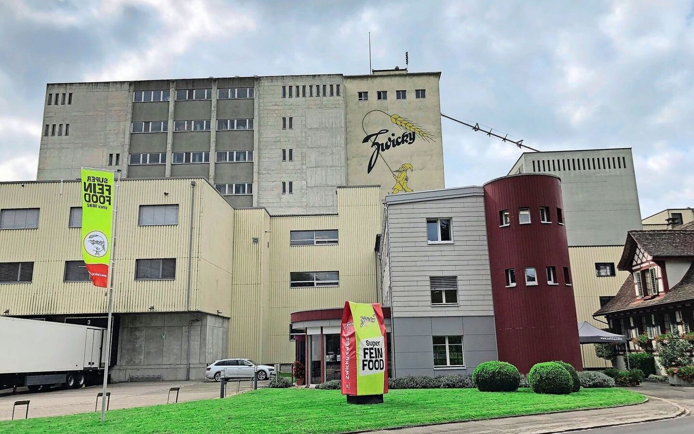 Im Bild zwei der drei Türme der Zwicky AG. Im markanten Gebäude mit dunkelrotem Rund ist der Fabrikladen eingerichtet. 