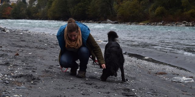 Murièle Jonglez mit ihrem Australian Shepherd Slash. Am Rheinufer unterhalb von Ilanz inspiziert sie Spuren von Hirschen. (Bild Stefanie Giger)