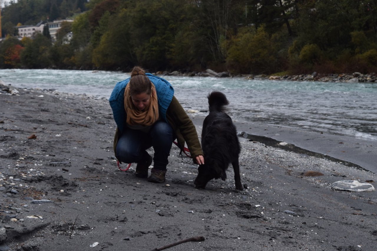Murièle Jonglez mit ihrem Australian Shepherd Slash. Am Rheinufer unterhalb von Ilanz inspiziert sie Spuren von Hirschen. (Bild Stefanie Giger)
