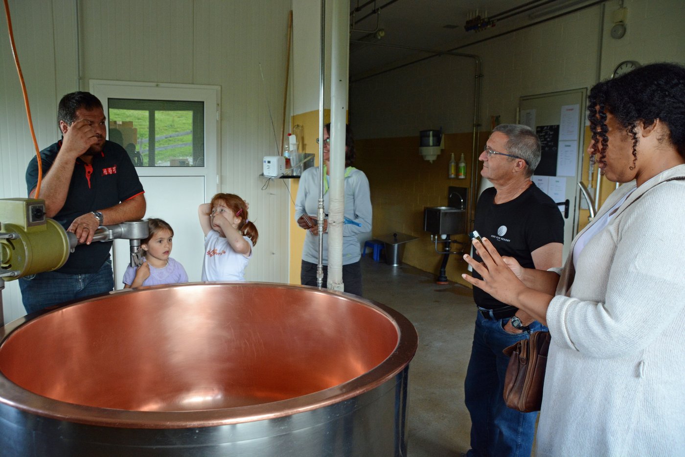 Reto Theiler (links) erklärt die Käserei, Daniel Hostettler (2. v. r.) übersetzt.