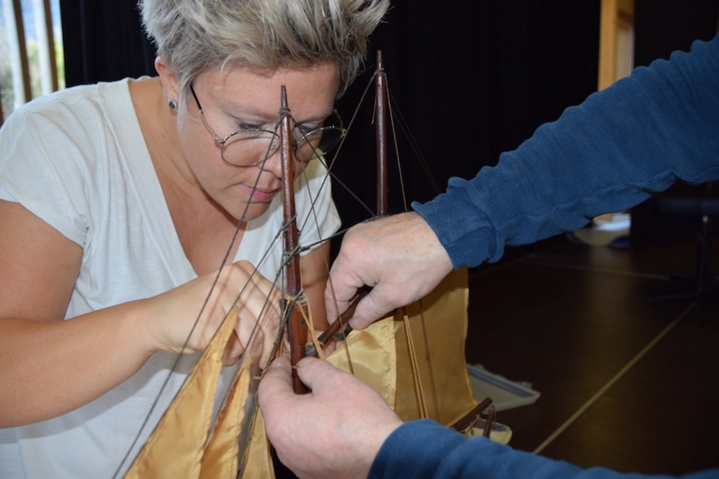 Das beschädigte Segel am Modellsegelboot wird gekonnt repariert.