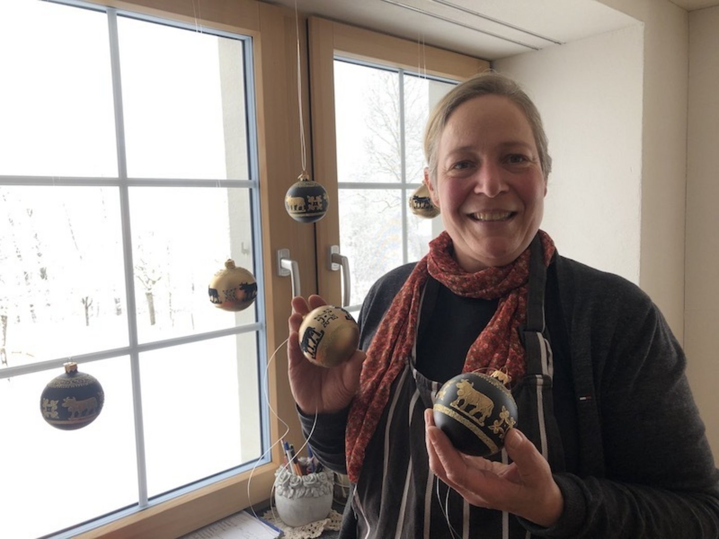 Weihnächtlicher Fensterschmuck für die Küche: Christbaumkugeln mit Kühen.