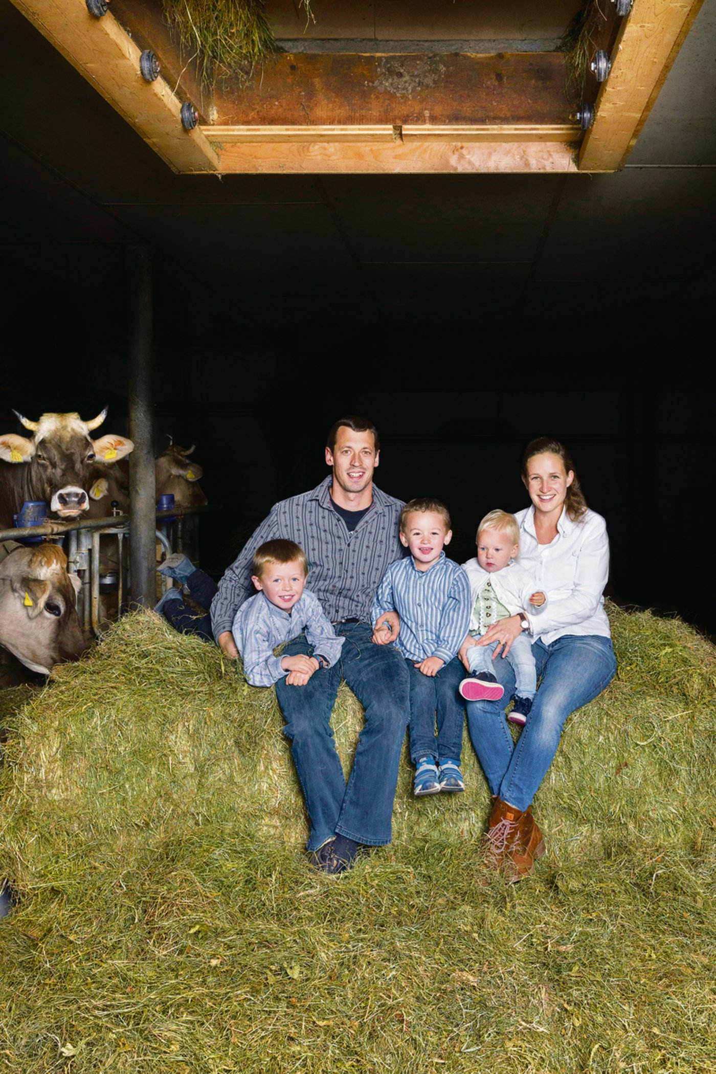Familie Hürlimann sitz auf dem Heu, das durch die selbstgebaute Heuschublade in den Stall plumpst.(Bild die grüne)