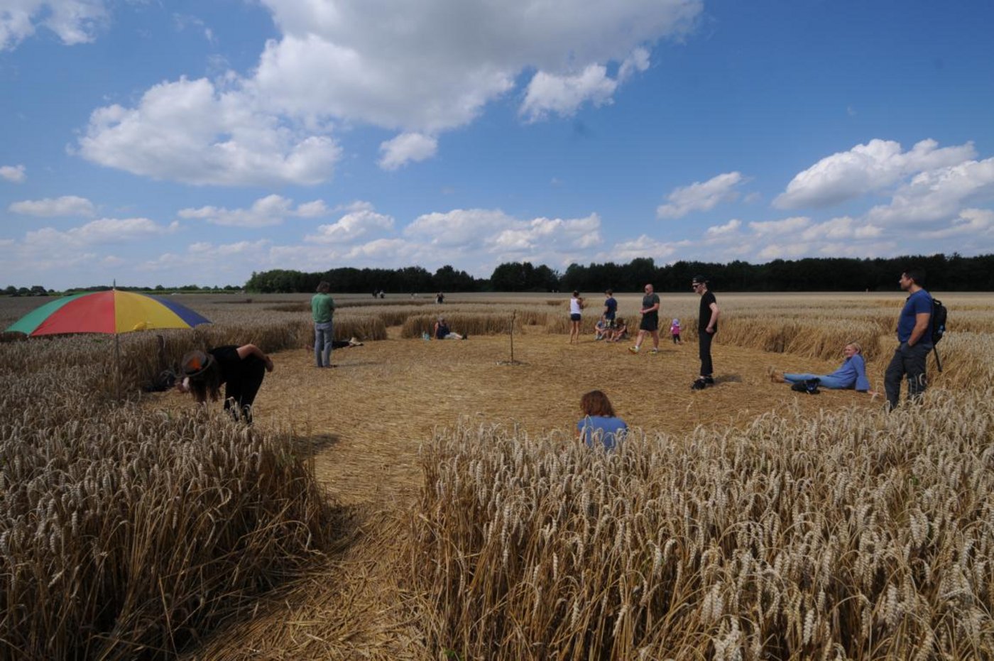 Im Zentrum des Kornkreises tummeln sich viele Menschen, die das Phänomen betrachten, meditieren oder sich einfach ausruhen. 