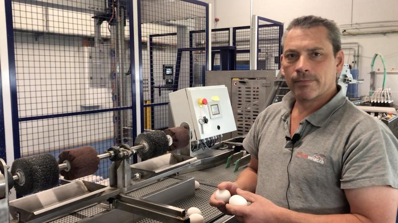 Markus Zürcher steht am Eiersortiertisch und erklärt den "Schöntal Ei Cleaner". dieser spart ihm einen Drittel der Arbeitszeit ein, die er und seine Mitarbeiterinnen zum Eier putzen benötigen.
