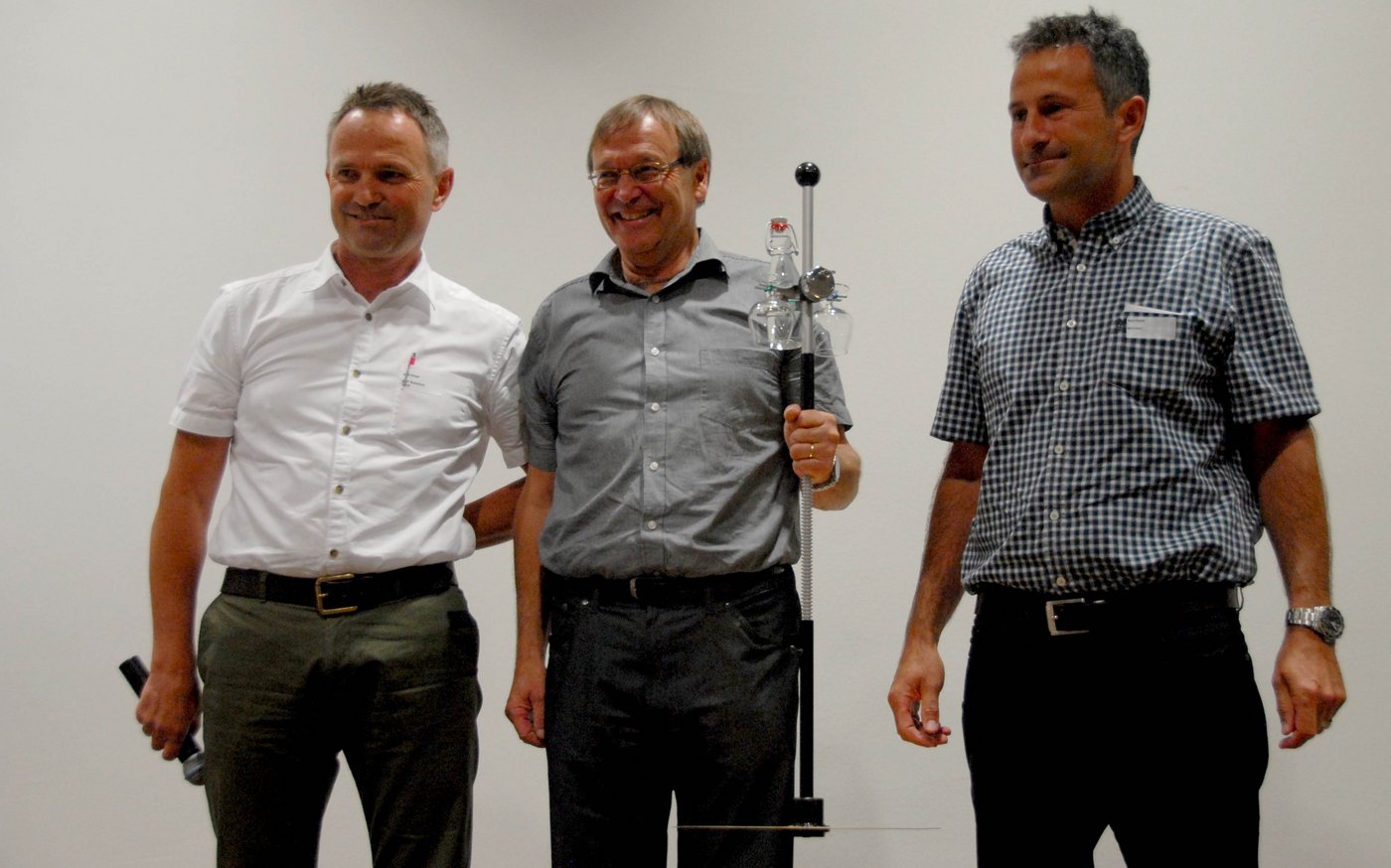 Willy Kessler, Geschäftsführer der AGFF-Sektion Deutschschweiz (links) und Beat Reidy (rechts), Dozent für Wiederkäuersysteme und Futterbau an der HAFL übergeben Peter Thomet zum Dank für seine Verdienste einen goldenen Rising Plate Meter (Zur Messung der Grashöhe). Thomet wird im Januar nächsten Jahres in den Ruhestand treten...