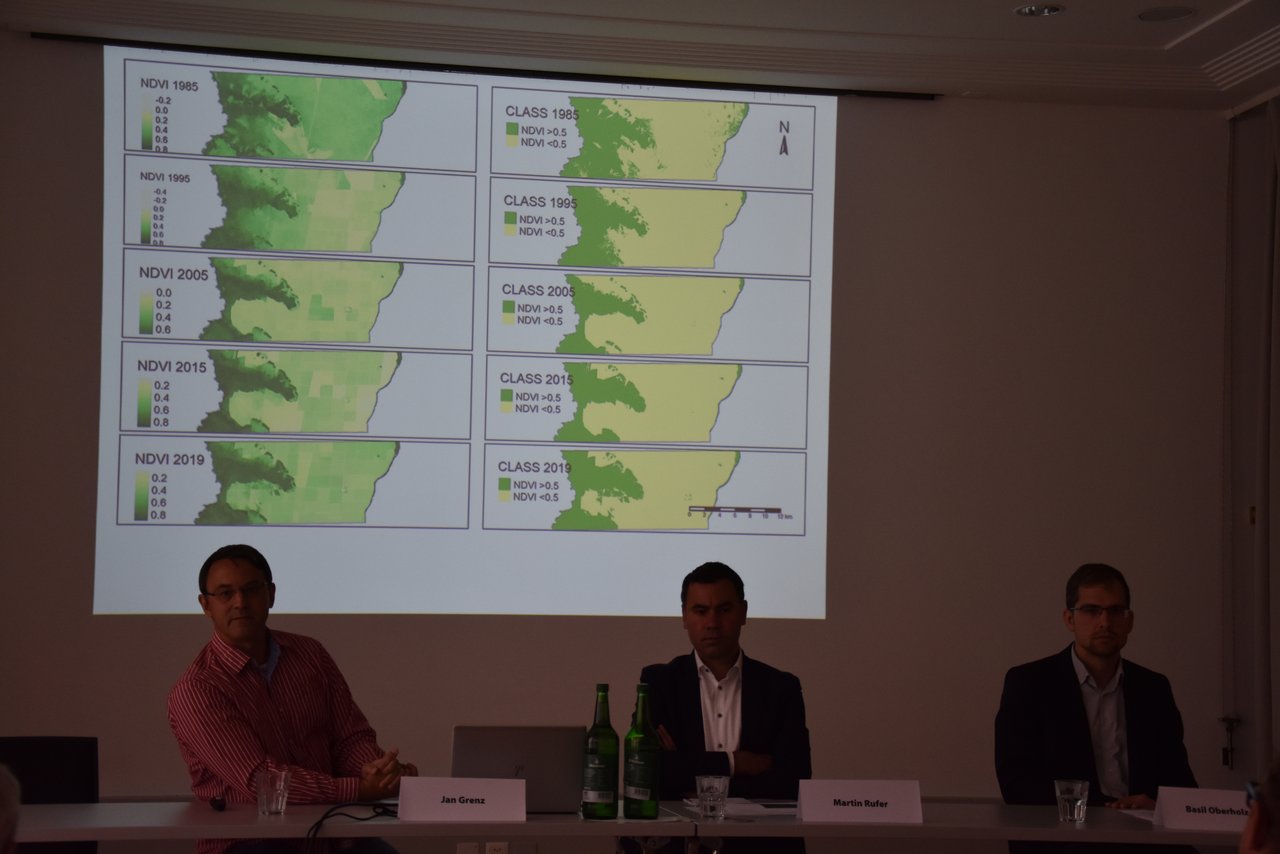 Die Referenten Jan Grenz (links), Martin Rufer und Basil Oberholzer an der Pressekonferenz von Verein Soja Netzwerk Schweiz in Bern. Das Bild im Hintergrund zeigt Satellitenbilder von der verbleibenden Regenwaldfläche in der Cerrado Region in Brasilien (Bild Bauernzeitung/Sera Jane Hostettler)