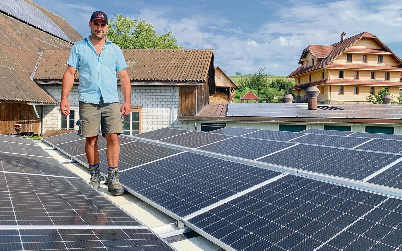 Adrian Bucheli auf dem mit PV-Modulen belegten überdachten Güllesilo. Solarstrom, auch für das sanierte Bauernhaus hinten, produziert er auch an der Scheunenfassade, auf dem Scheunendach (l.) und über dem Schweinestall (hinten). 