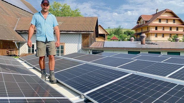 Adrian Bucheli auf d Adrian Bucheli auf dem mit PV-Modulen belegten überdachten Güllesilo. Solarstrom, auch für das sanierte Bauernhaus hinten, produziert er auch an der Scheunenfassade, auf dem Scheunendach (l.) und über dem Schweinestall (hinten).