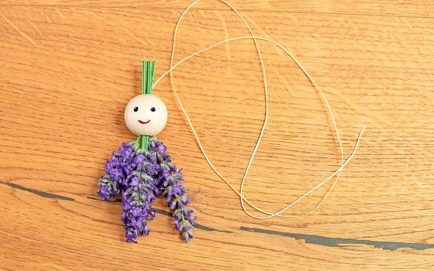 Die Holzkugel aufgefädelt und ein Gesicht gemalt.