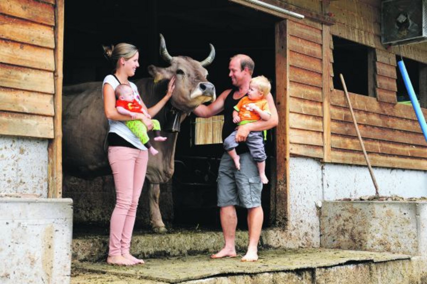 Dominik und Andrea Glaus mit Baby Lars (links) und Sohn Jan sowie mit der ältesten Kuh, die in ihrem Laufstall steht. (Bilder Barbara Schirmer)