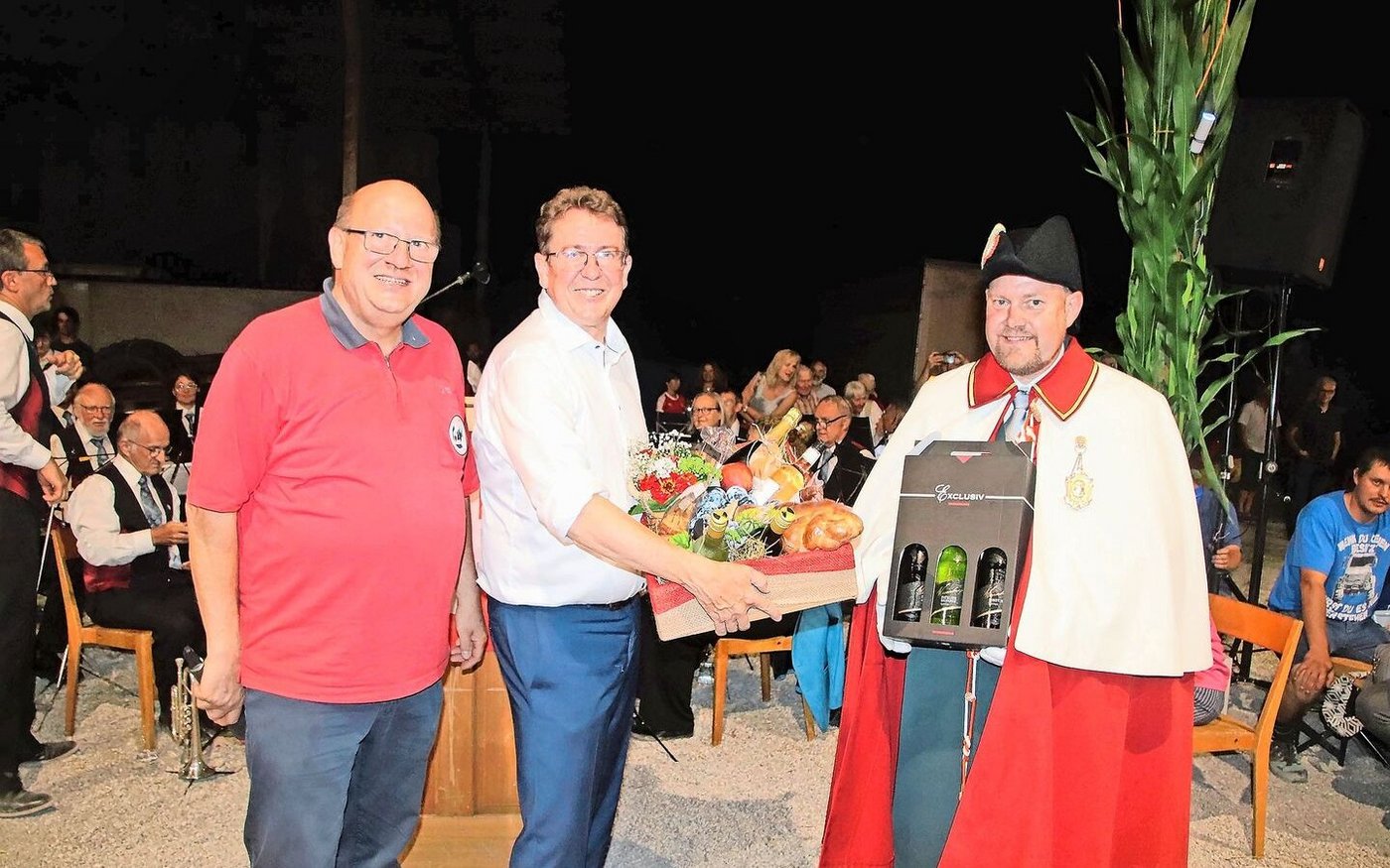 Urs Stähli, Präsident des Schützenvereins Ossingen, dankt Bundesrat Albert Rösti mit einem grossen Geschenkkorb und drei Flaschen Wein, die sein Weibel Carlo Pfister für ihn in der Hand hält (v. l.).