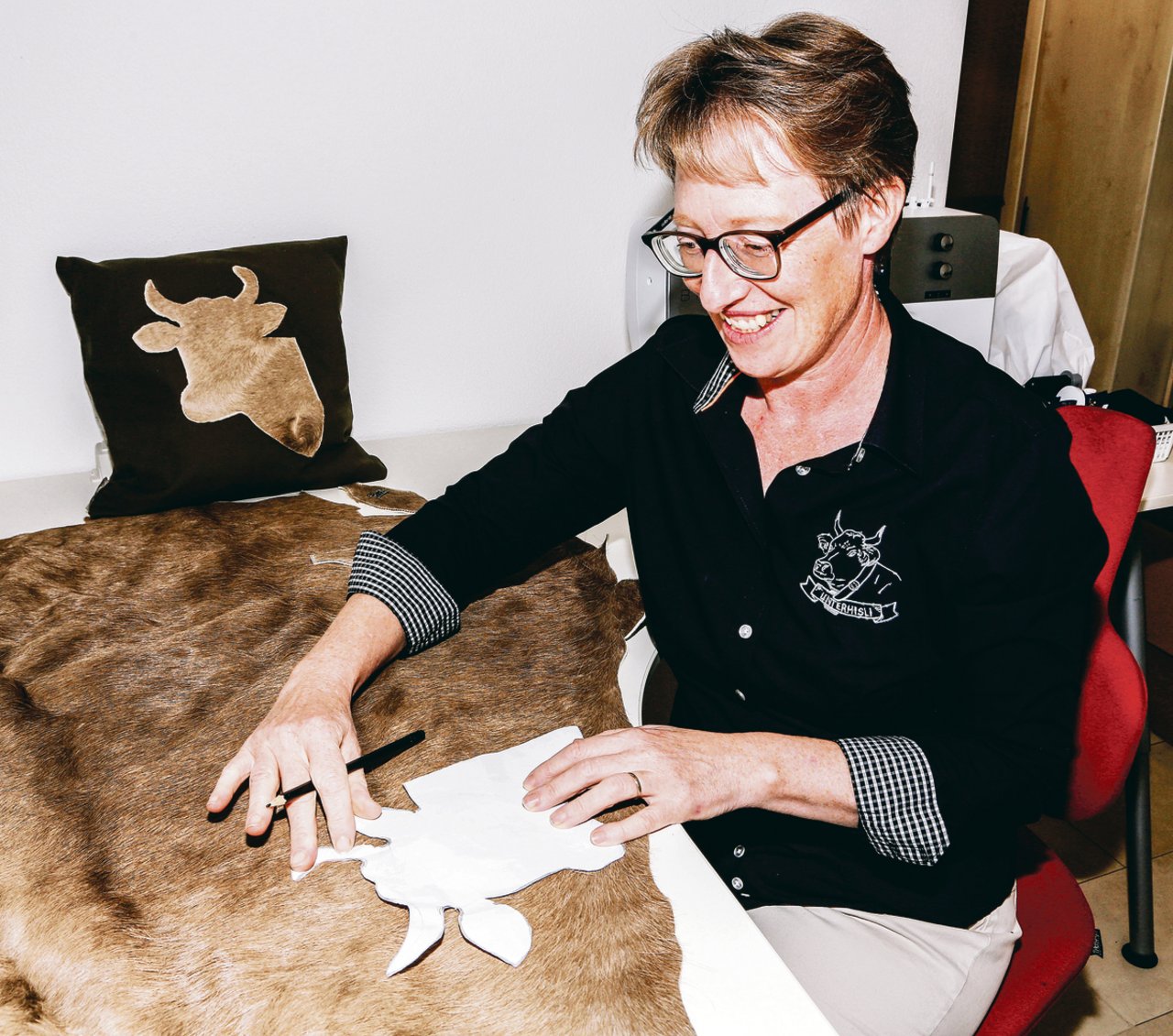 Irene Amstutz fertigt aus dem Fell ihrer Kuh Pamela in Eigenkreation Kissen mit Kuhkopfsujet für die Skyboutique des Bürgenstock-Resort an. (Bild Erika Rebsamen)