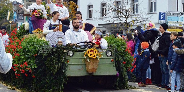 Sennenammann Albert Gössi und seine Frau Paula grüssen von einem prächtig geschmückten Umzugswagen.