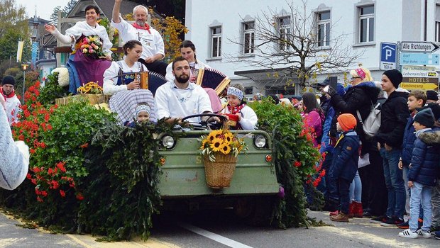 Sennenammann Albert Gössi und seine Frau Paula grüssen von einem prächtig geschmückten Umzugswagen.