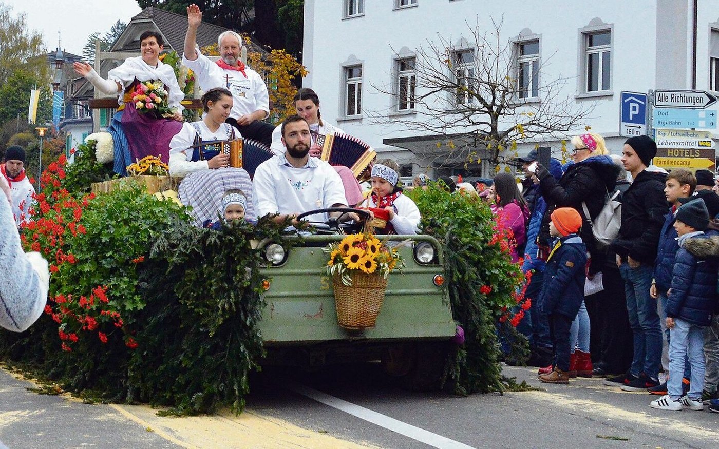 Sennenammann Albert Gössi und seine Frau Paula grüssen von einem prächtig geschmückten Umzugswagen.