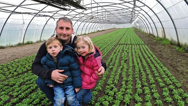 Gemüsebauer Christoph Johner mit den dreieinhalbjährigen Zwillingen Julian und Leonie im Gemüsebautunnel, wo Nüssli-Salat wächst. (Bild Josef Jungo)