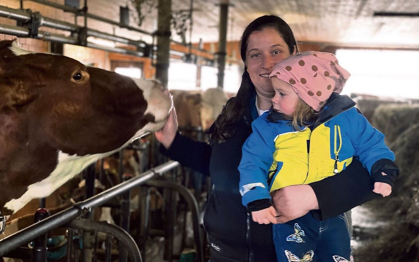 Im Anbindestall stehen Swiss-Fleckvieh-Kühe. Doris Friedli (hier mit der zweijährigen Tochter Kerstin) hilft auf dem Hof, wo es sie braucht. 