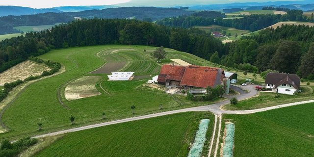 Auf dem Luftbild vom Juni 2023 sind die geschwungenen Gemüsefelder gut erkennbar. Auf dem Hof selbst ist ein Speicherbecken für Dach- und von der Ackerfläche abfliessendes Regenwasser geplant.