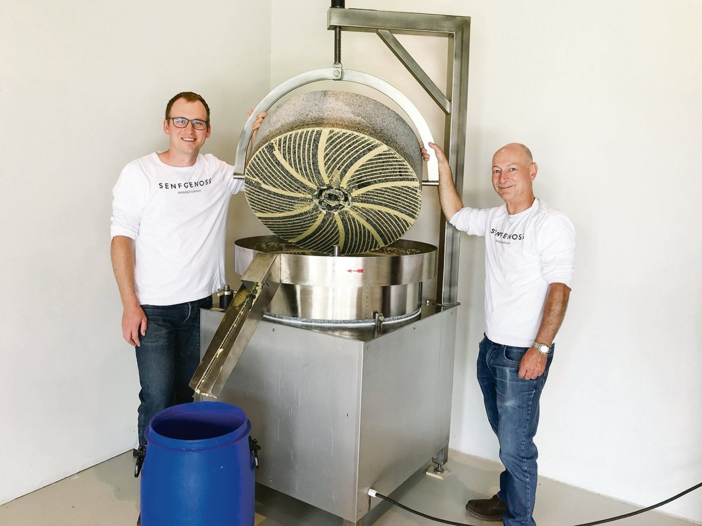 Ueli Kilchsperger (links) und Beat Voegeli zeigen die Steinmühle mit den 300 Kilogramm schweren Granitscheiben, zwischen denen die Maische zu Senf vermahlen wird.(Bilder Alexandra Stückelberger)