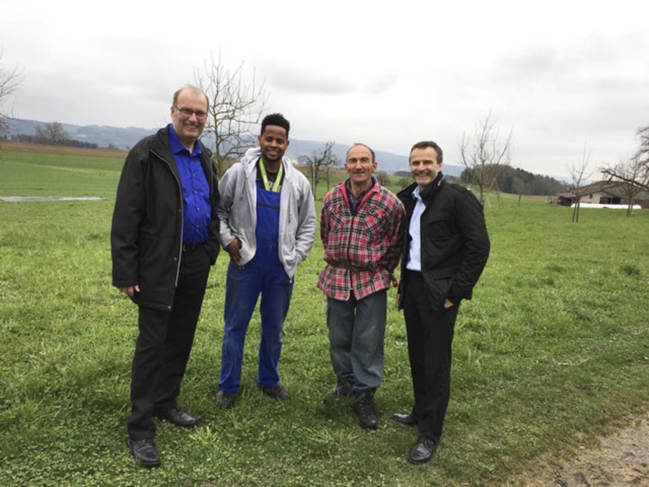 Markus Ritter (SBV-Präsident), Tesfu Adhanom (auszubildender Agrarpraktiker), Markus Ramser (Betriebsleiter) und Urs Schneider (stv. Direktor SBV) auf dem Hof im Kanton Thurgau. (Bild SBV)