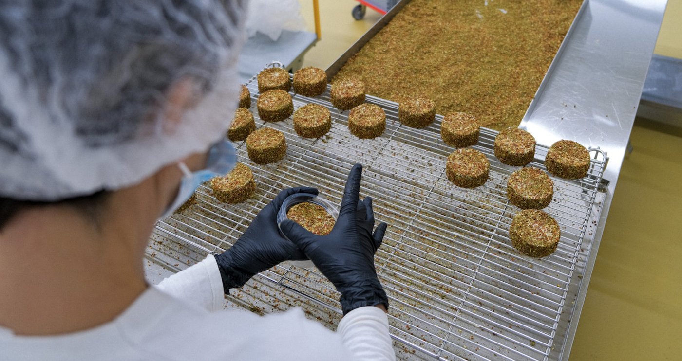 Bei New Roots ist Vieles Handarbeit. Hier bekommt der Käse-Ersatz seinen Kräutermantel. (Bild New Roots)